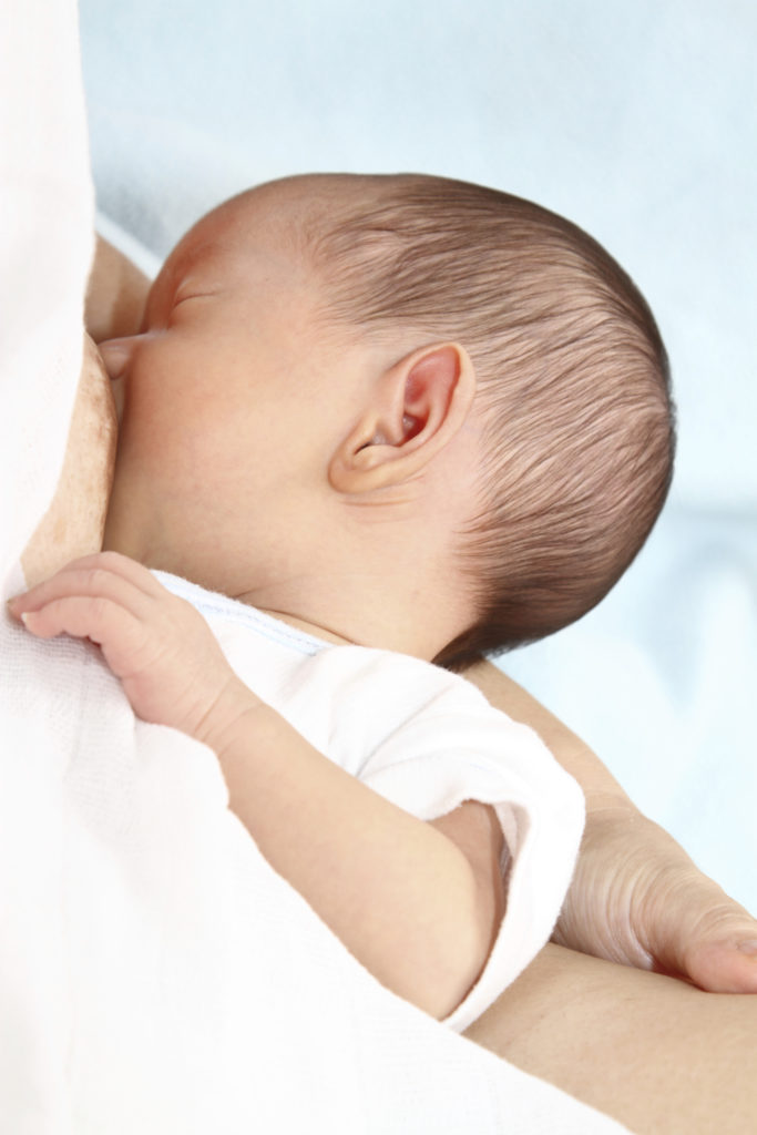 Closeup of a baby nursing from its mother's breast