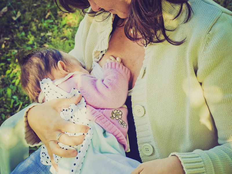 A mother holding and nursing her newborn baby