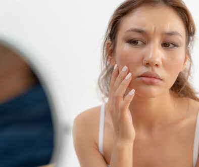 Closeup of a Young Woman Concerningly Looking at Her Face in a Mirror Experiencing the Effects of PCOS