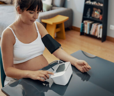 A Pregnant Woman Sitting Down Wearing A Blood Pressure Cuff Checking Her Blood Pressure What Is Preeclampsia